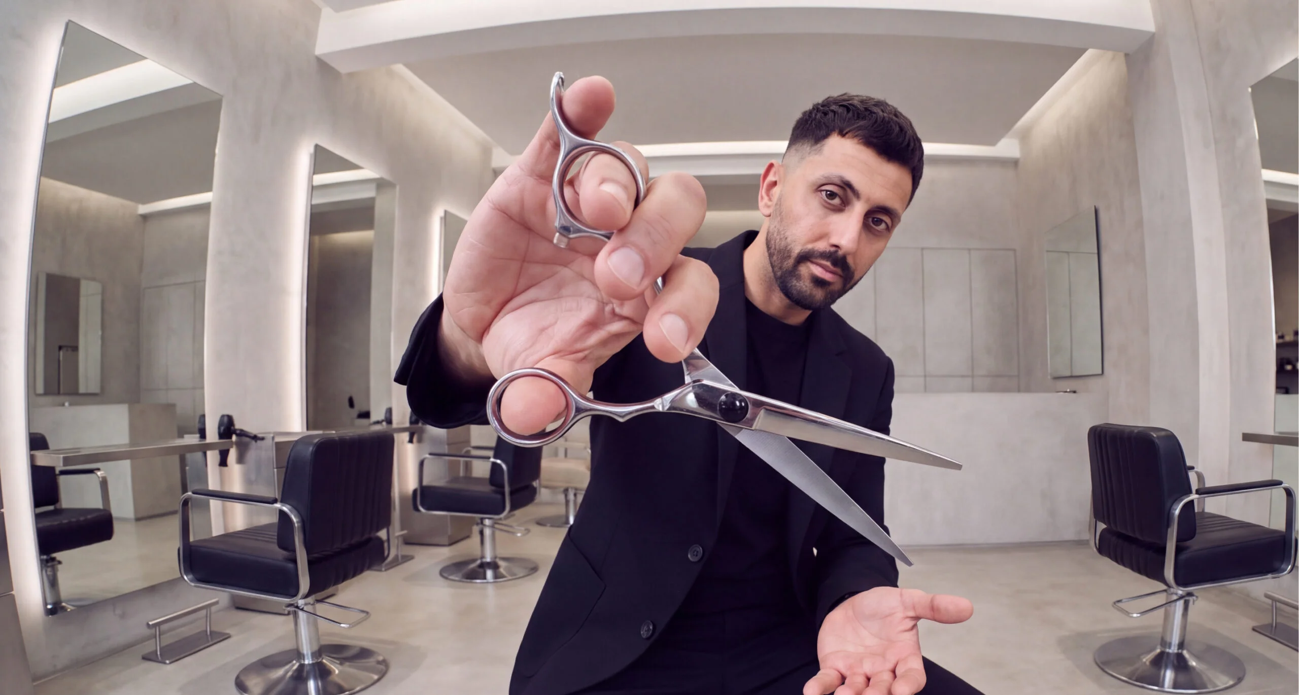 Un coiffeur présente une paire de ciseaux dans son salon.